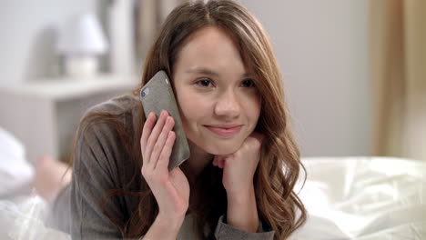 Mujer-Joven-Hablando-Por-Teléfono-Móvil-En-La-Cama.-Mujer-Sonriente-Hablando-Por-Teléfono