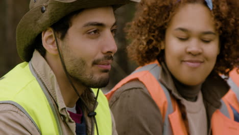 close-up view of a group of multiethnic ecologist activists eating and talking in a break in the forest