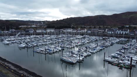 Scenic-luxurious-waterfront-harbour-apartment-village-yachts-and-sailboats-under-mountain-coastline-aerial-view-push-in-right