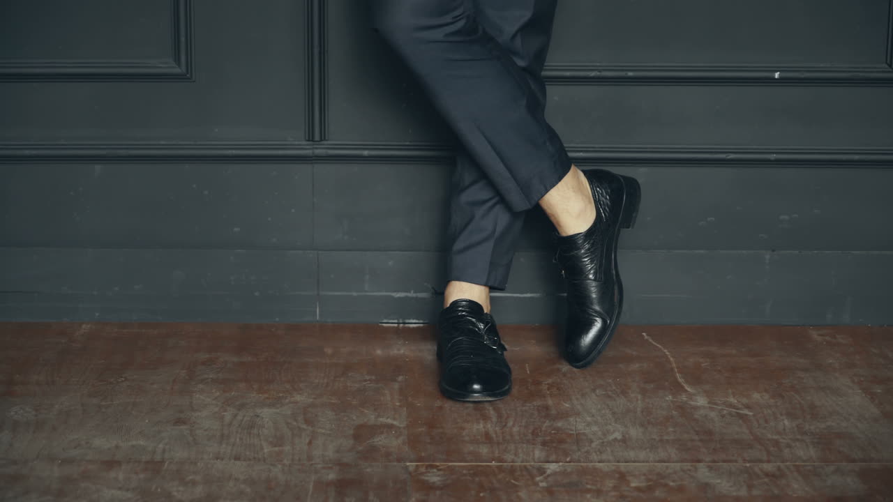 Close-up Kaki Pria dengan Sepatu Elegan. Kaki pria dengan sepatu klasik di latar belakang hitam.