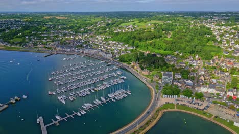 Perros-Guirec harbor with sailboats, coastal town, bridge, and green countryside, Brittany, France. Aerial drone backward