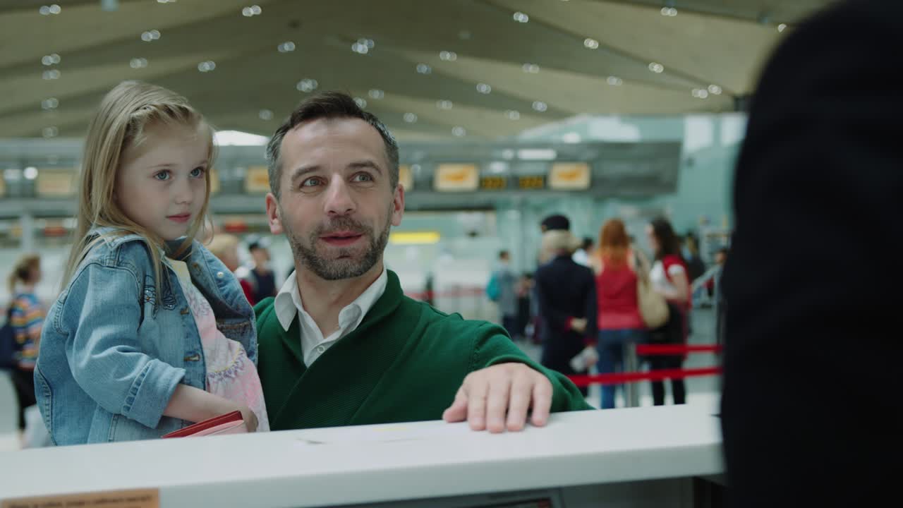 tímida niña linda en las manos de los padres tomando boletos para el vuelo desde el lugar de check-in.. terminal del aeropuerto. toma cinematográfica en cámara roja.