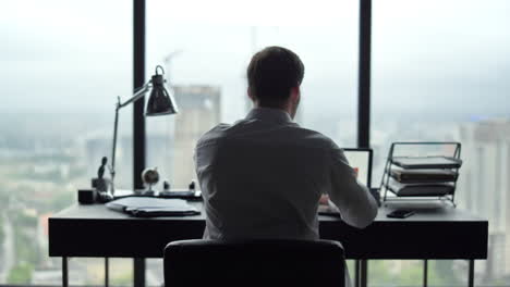 Businessman-reading-papers-at-workplace.-Manager-looking-at-graphs-on-laptop