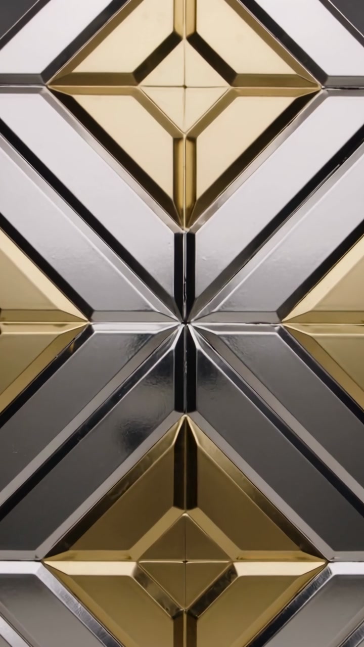 Vertical video: Camera moving lifting highlights along metal panel in studio, showing gold pyramids