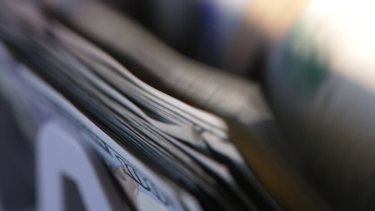 Hundred dollar bills wad turned quickly in machine. Cash counting device for financial operations. Close up.
