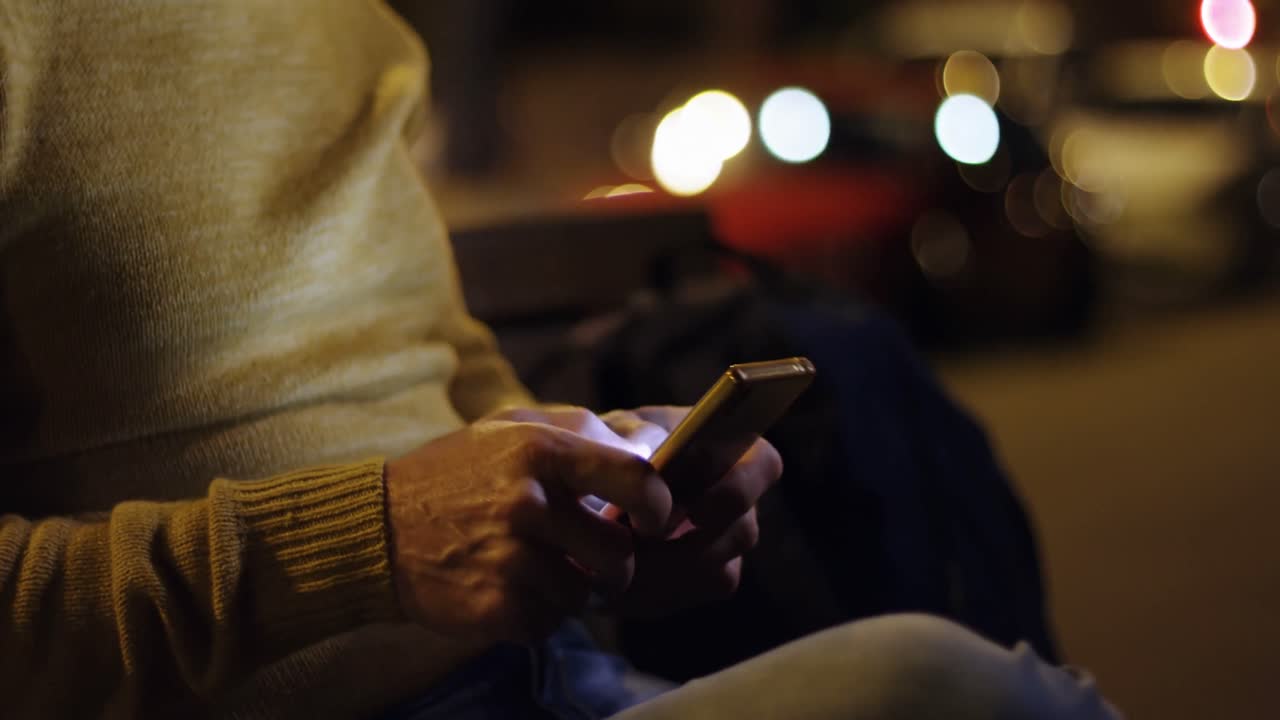 Uomo anziano che usa il cellulare in città di notte 4k