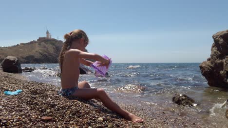 cabo de gata, spain - a girl is engaging in pebble play at the seashore - wide