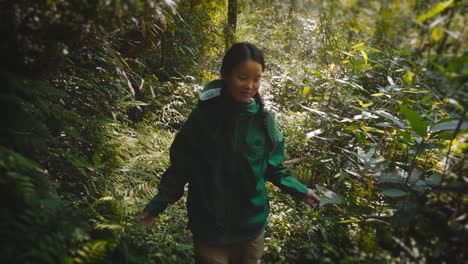 enthusiastic young asian woman exploring jungle vegetation at sunset