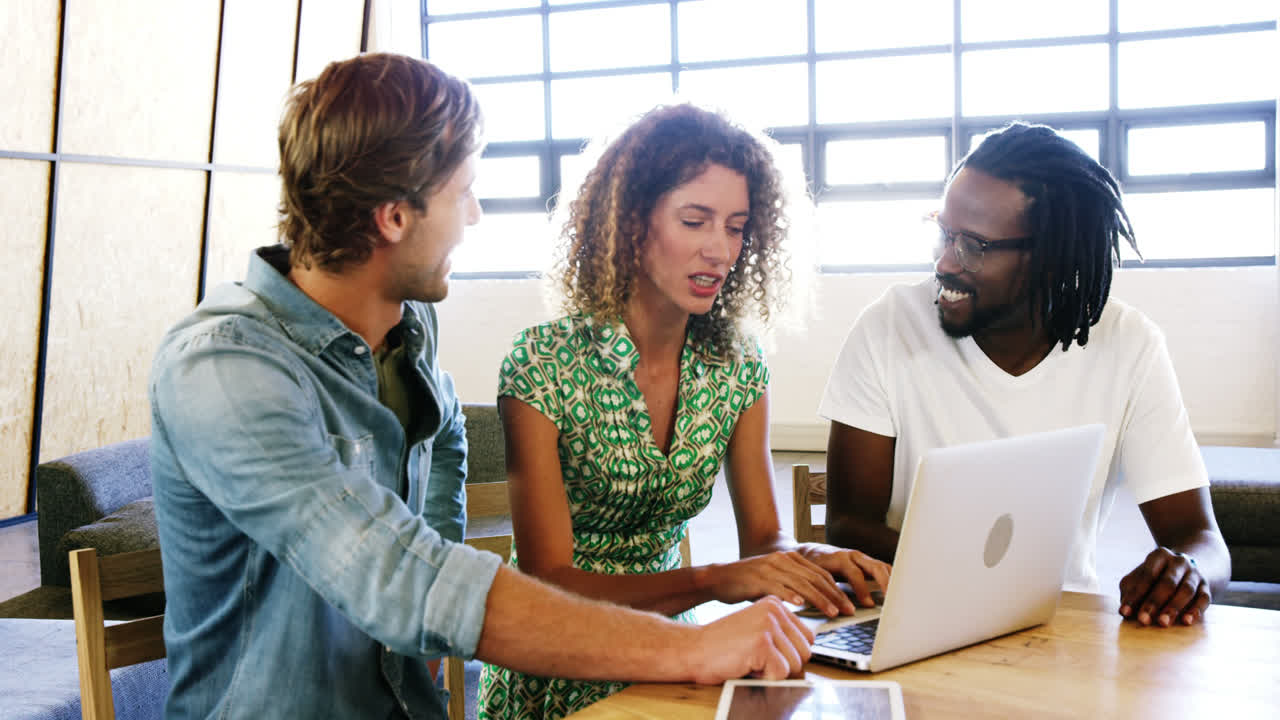 Colleagues discussing with each other over laptop