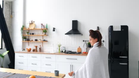 mujer disfrutando de una bebida caliente en la cocina