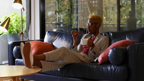 Young-black-businessman-drinking-coffee-and-talking-on-mobile-phone-in-modern-office-4k