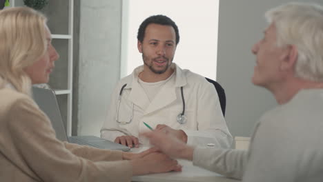 a young black doctor in a medical consultation with a ederly couple