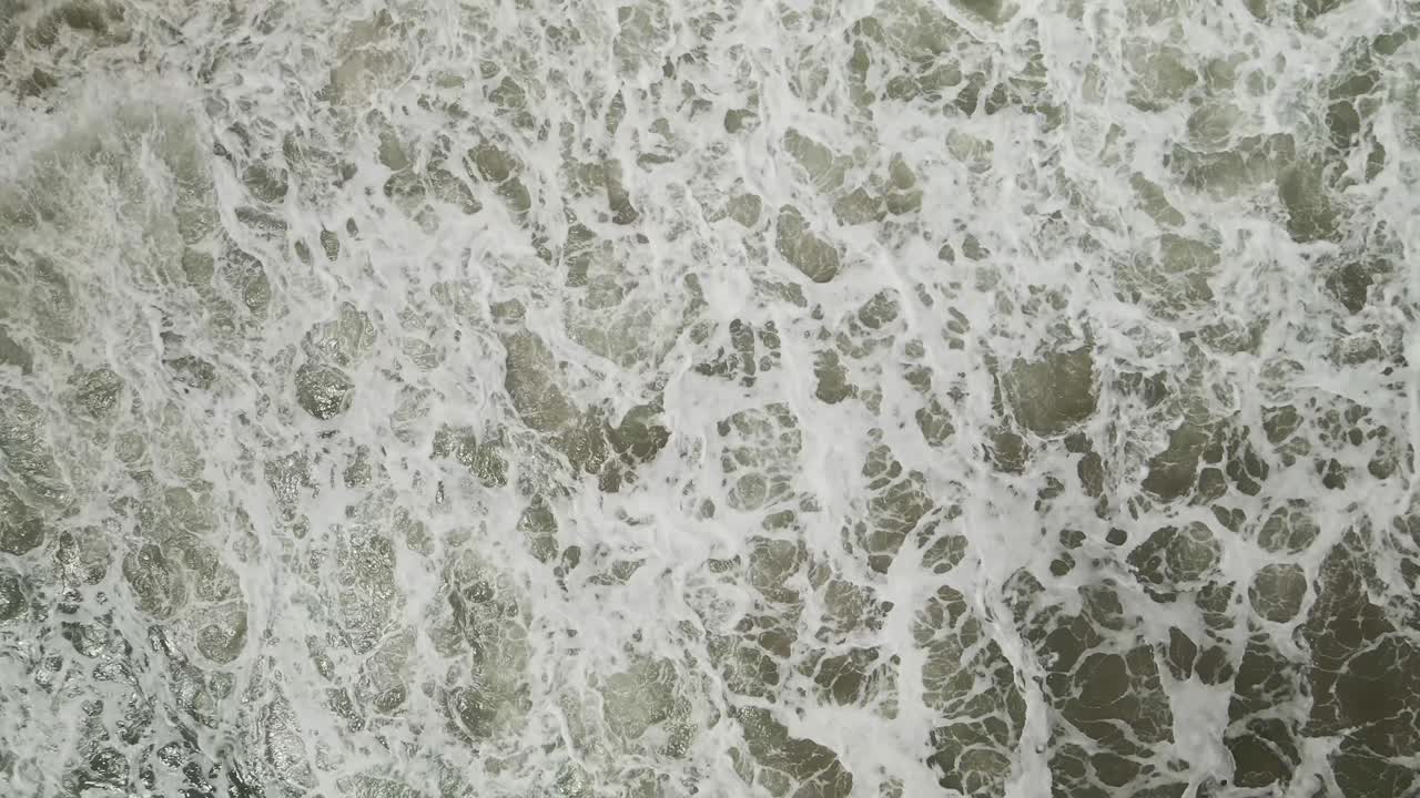 Ascending aerial over waves crashing on beach