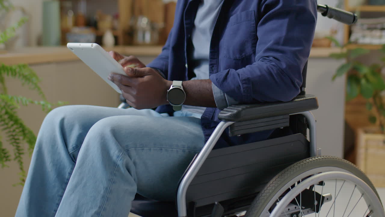Man in Wheelchair Using Digital Tablet at Home