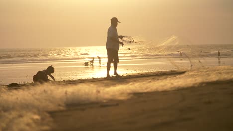 man folding fishing net at sunset