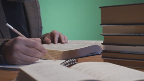 hombre estudiando con libros y bloc de notas en el escritorio, fondo de pantalla verde 4k