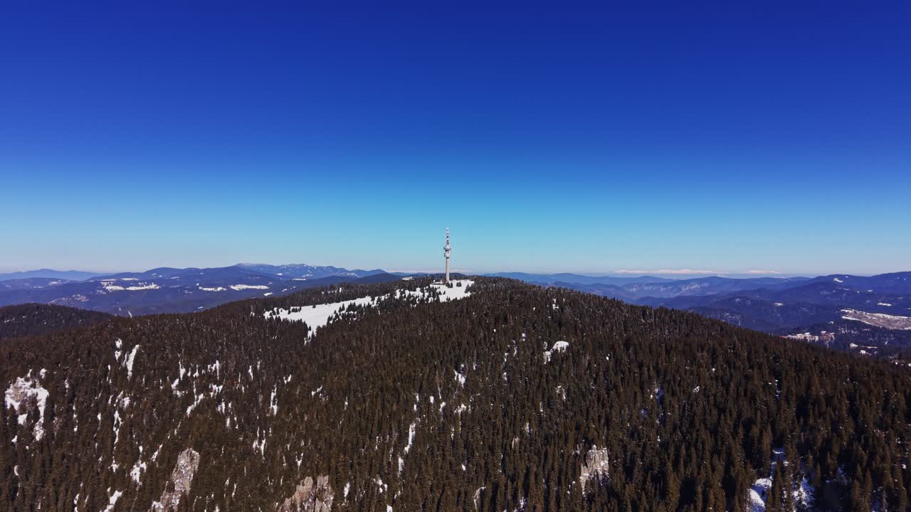 Udsigt over Karpaterne i Bulgarien med et tårn på et sneklædt bjerg.