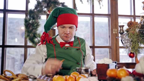 elf eating at a table. santas elf eating christmas dinner in a decorated room. new year celebration. christmas eve.