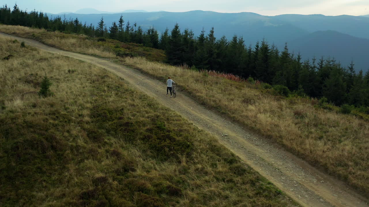 Aerial view mountain biking on hilly grassy road against blue sky enjoying