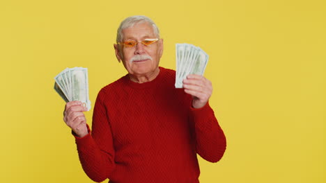 Senior old winner man holding fan of cash money dollar banknotes celebrate dance success pension