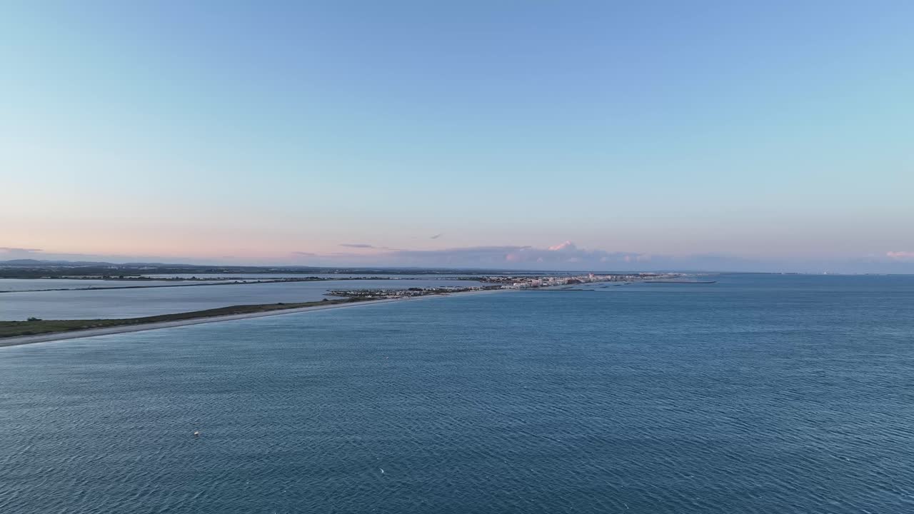 Coastal town of Palavasles Flots in southern France at dusk with sandbar coastline, Aerial approach shot