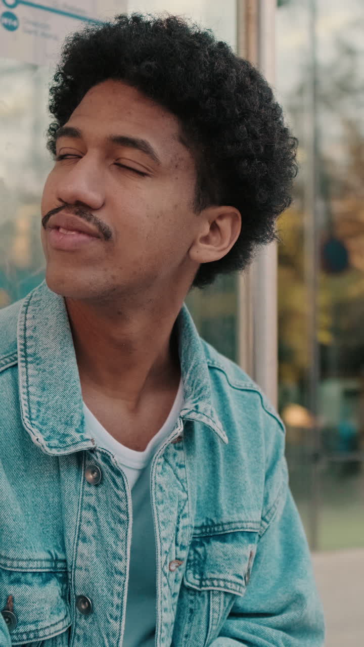 Young Man with Curly Hair and Mustache Looking Around Thoughtfully
