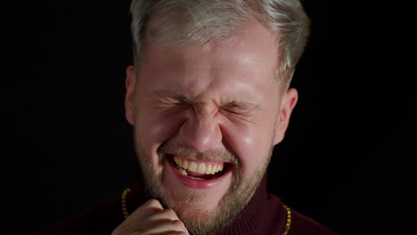 smiling stylish young man looking at camera, laughting at loud after funny joke, feeling happiness