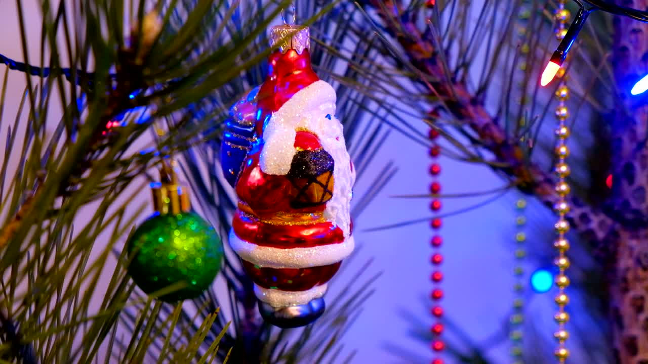 decoración de navidad y año nuevo. cubo colgado de cerca. fondo de vacaciones de bokeh borroso abstracto. guirnalda parpadeante. luces de árbol de navidad parpadeantes. juguete de santa claus