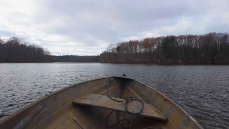 experience a serene point-of-view journey from the front of a boat as it glides smoothly across a tranquil lake. surrounded by lush green trees and a expansive blue sky.