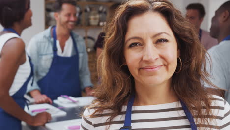 Retrato-De-Una-Mujer-Madura-Sonriente-Con-Delantal-Participando-En-Una-Clase-De-Cocina-En-La-Cocina