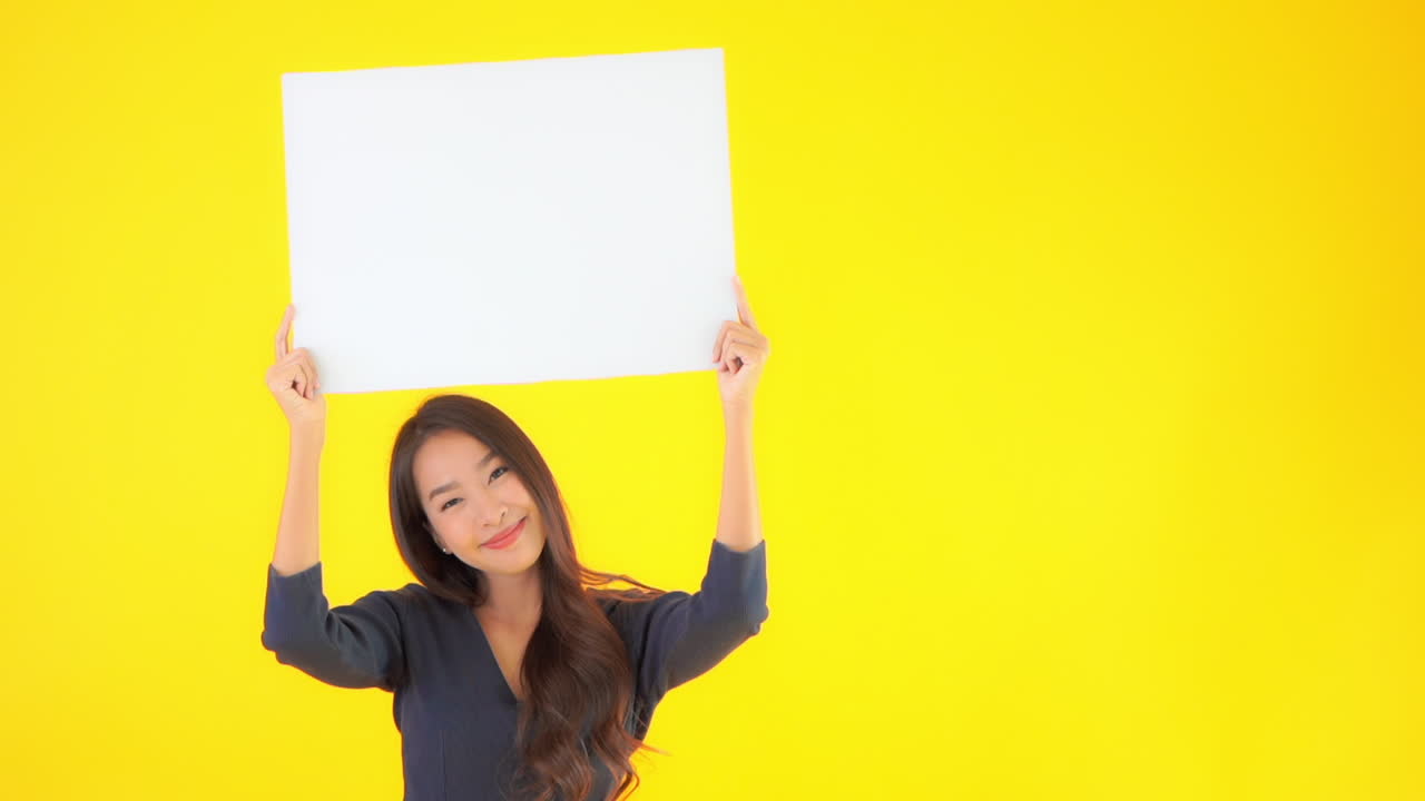 Asian lady holding a blank sheet of the paper poster banner above her head with a happy face expression