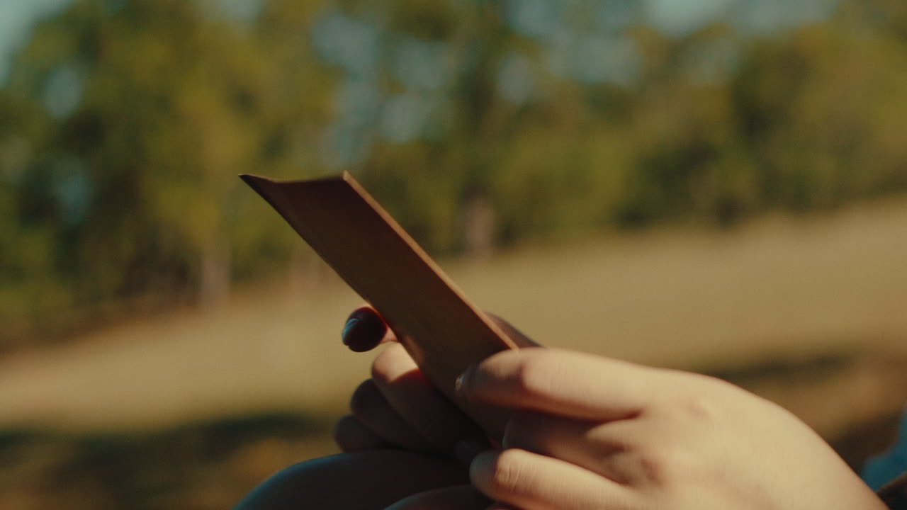 Hands holding a piece of paper outdoors