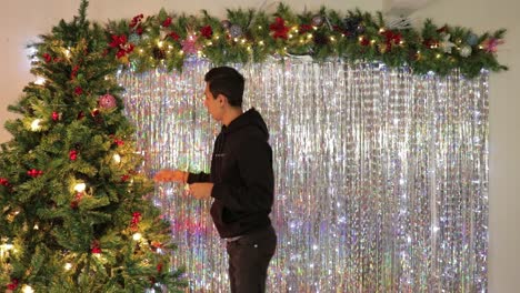 young mexican man decorating christmas tree in festive room, timelapse