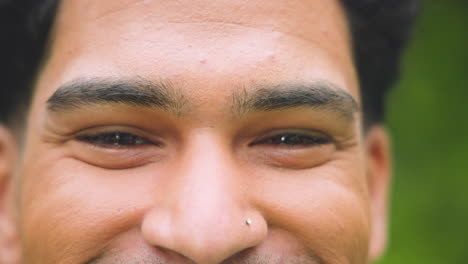 close-up of young man smiling outdoors, showing joy and happiness