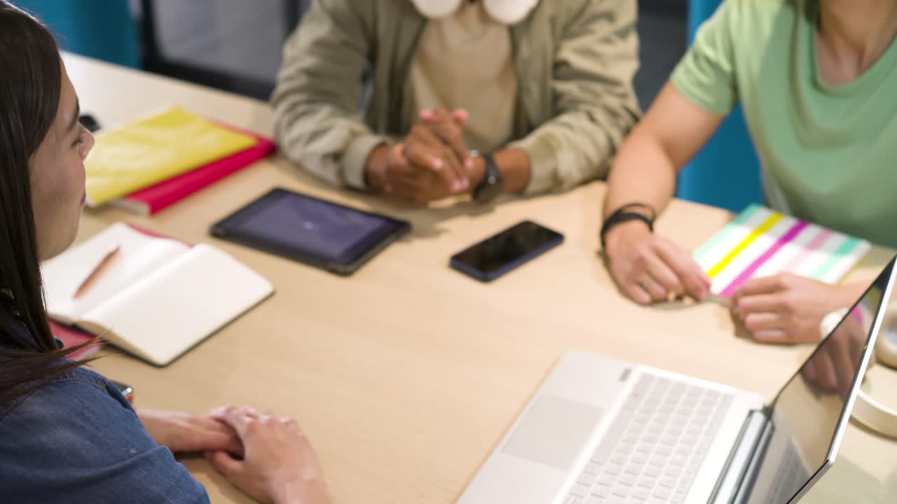 Diverse students starting work at study hub after headphones man leaning forward, typing on laptop