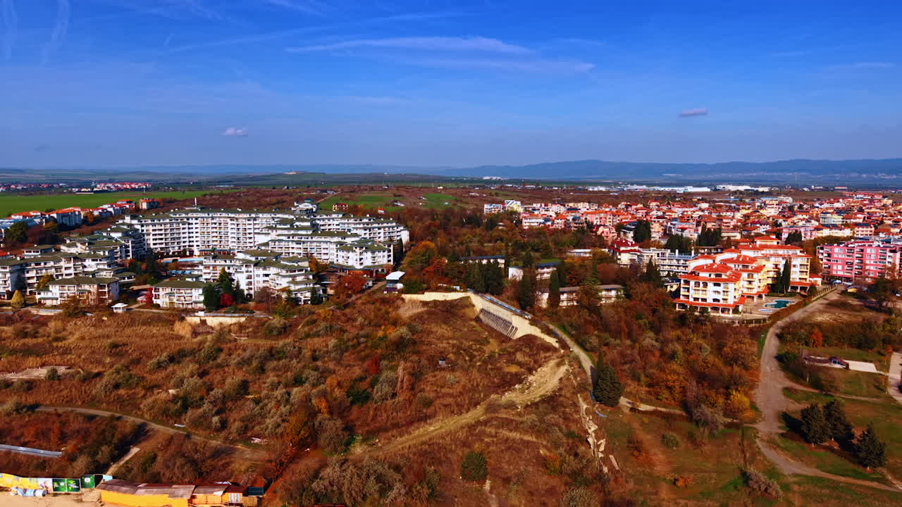 Approaching sandy beach with several piers. Aerial perspective on the modern buildings in the lush vegetation in early autumn season