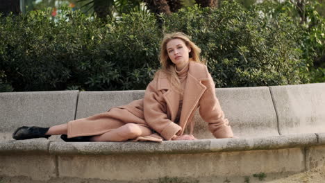 young woman lying on bench and looking at the camera.