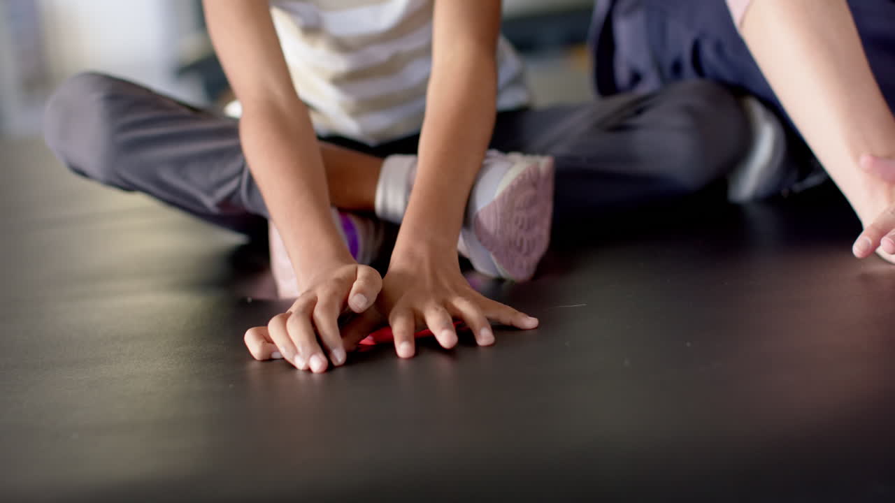 Girl with cerebral palsy in disability rehab stretching hands on floor during therapy session