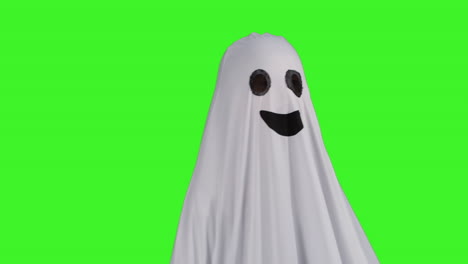 child dressed up in ghost costume trick or treating at halloween scaring people in front of studio green screen