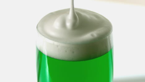 Cerca-De-Espuma-Vertiendo-Sobre-Una-Pinta-De-Cerveza-Verde