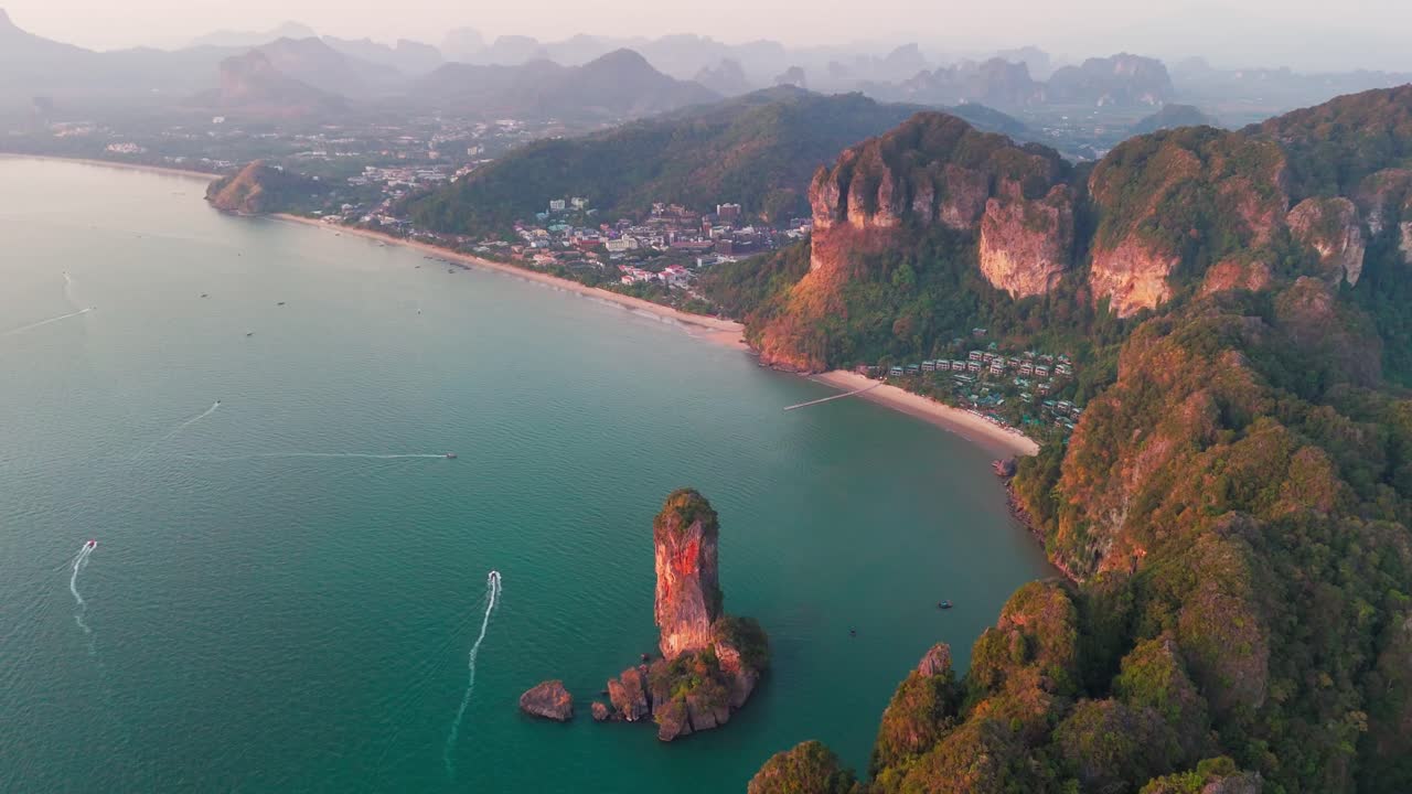 Drone establishing of Nang Beach in Krabi, Thailand, dramatic limestone cliffs and blue sea with boats headed to shore