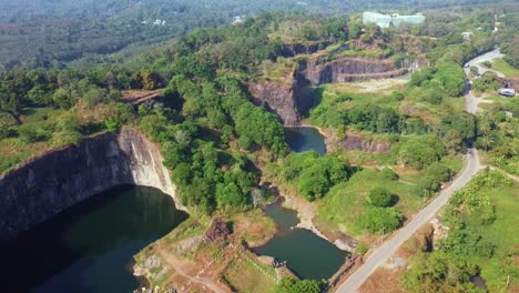aerial view of a vast rock quarry in india with deep water pits, rugged cliffs, greenery and winding roads. ideal for mining, geology, environment, industry, natural landscapes and drone perspective
