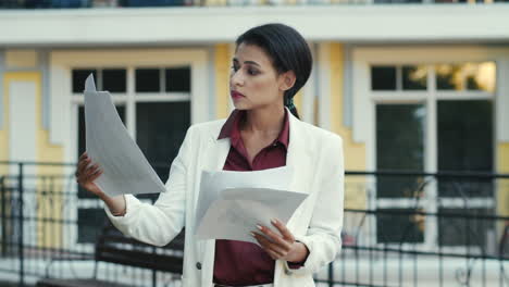 businesswoman reading documents at urban street. woman looking project papers