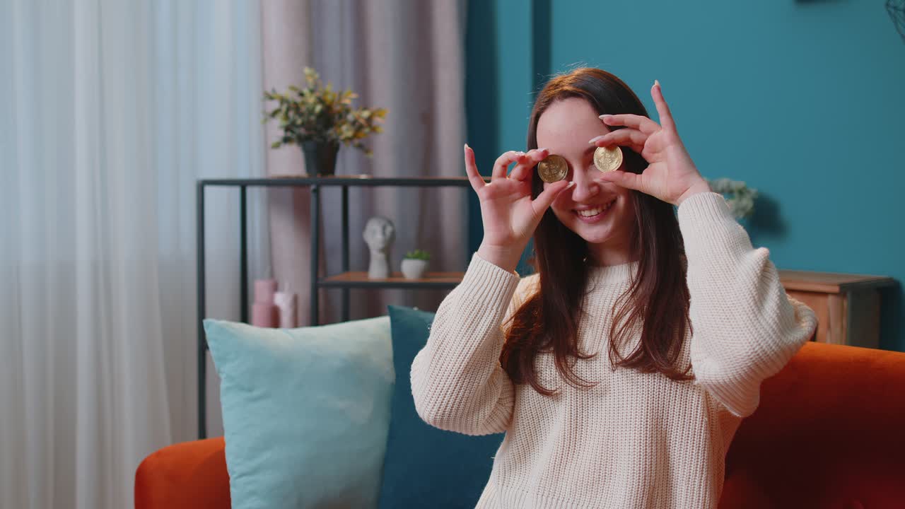 Woman freelancer holding two gold coins btc at home successful developer programmer stock trader