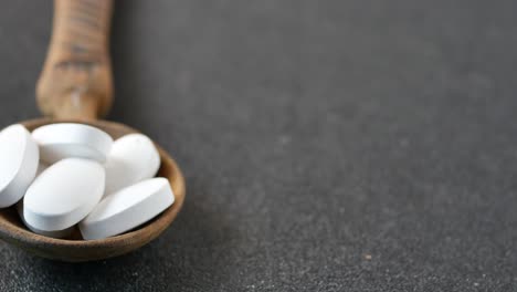 white pills and brown capsules in wooden spoons