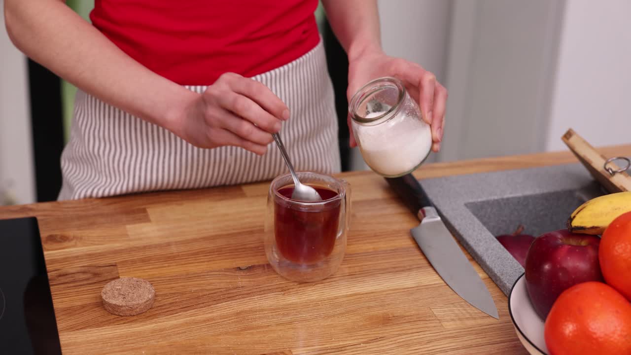 Adding sugar to tea in the kitchen