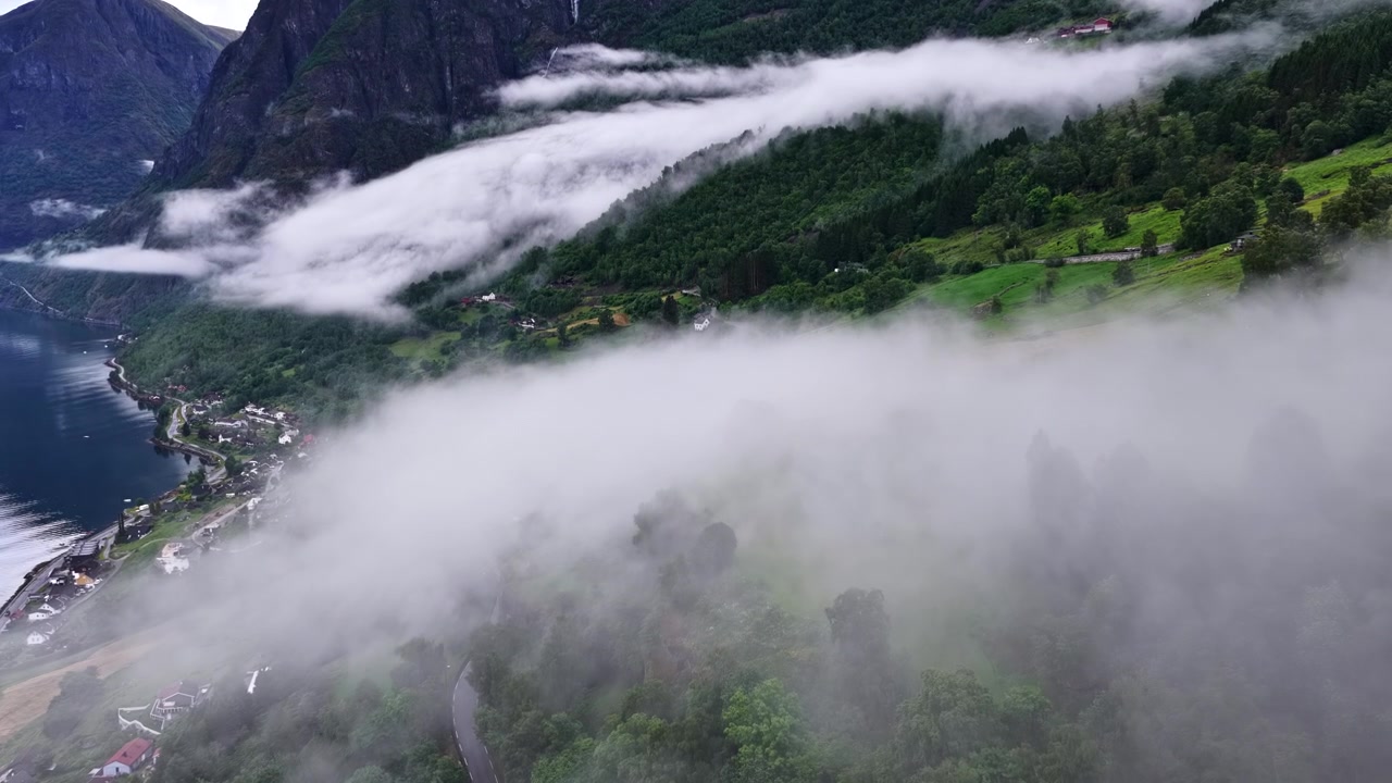 Tief fliegende Wolken über malerischem norwegischem Fjord und Bergen mit üppig grünem Vordergrund