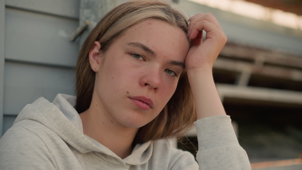 한 여자가 깊은 숙고의 순간에 그녀의 손에 머리를 고, 그녀의 눈은 천천히 이고, 그녀의 표정은 부드러운 배경과 함께 내성과 사려 깊음을 드러니다.