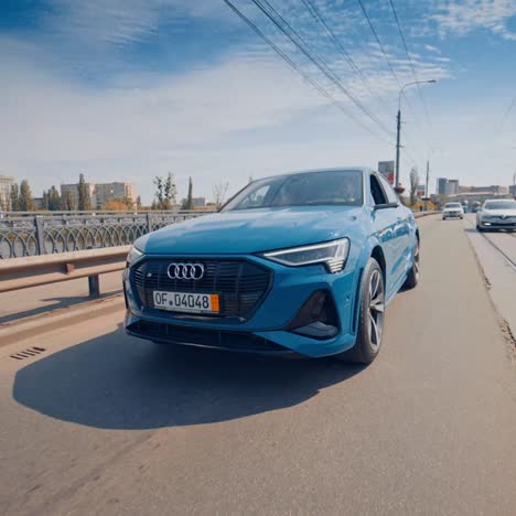 luxurious blue audi e-tron. new car driving on asphalt road through city