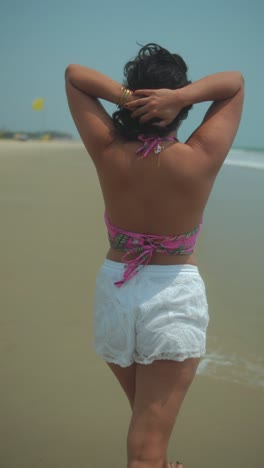 young woman walking along the beach, relaxing in the sun, with a breeze flowing through her hair